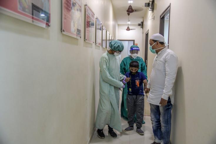 Nuestros enfermeros acompañan a un niño de 9 años con tuberculosis a la sala de electrocardiogramas, en nuestra clínica independiente en Mumai. India, marzo de 2021