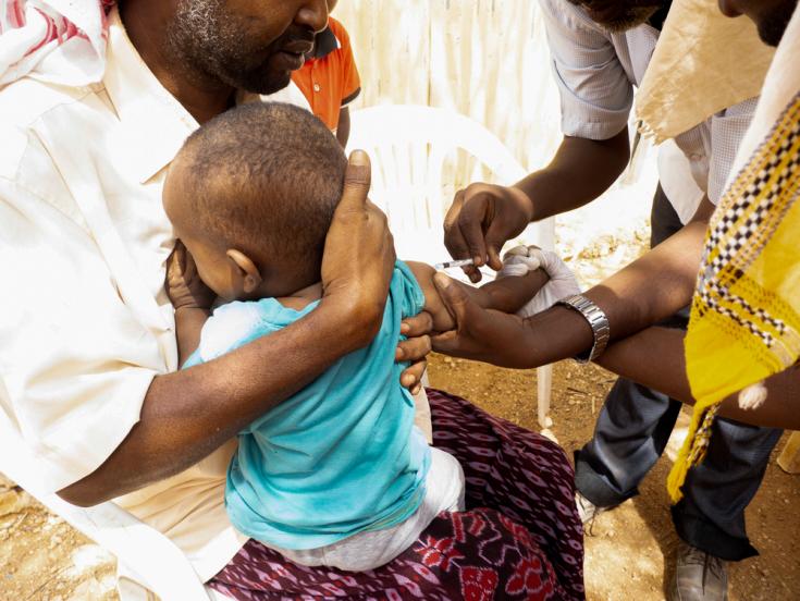 Un padre sostiene a su hijo mientras es vacunado contra el sarampión en Burao, Somalilandia