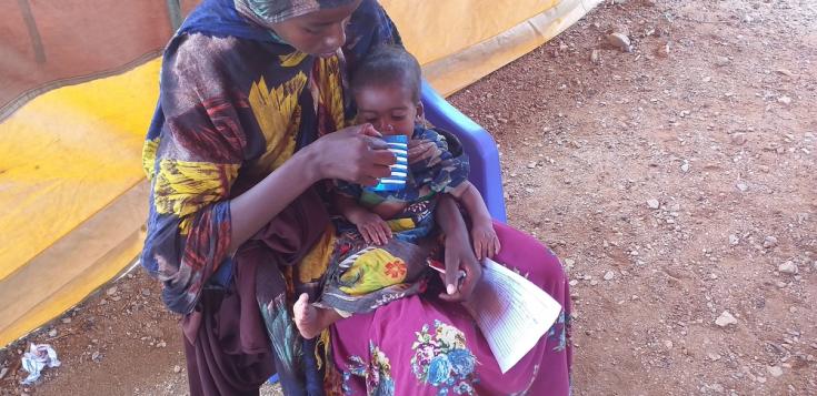 Madre alimenta a hijo en centro ambulatorio de alimentación terapeútica de MSF, Baidoa