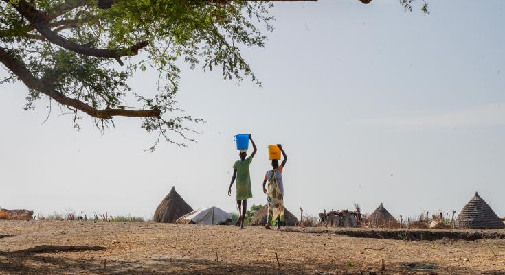Dos mujeres transportan agua sobre sus cabezas desde el río hasta sus casas en el condado de Akoka, en el estado del Alto Nilo, Sudán del Sur