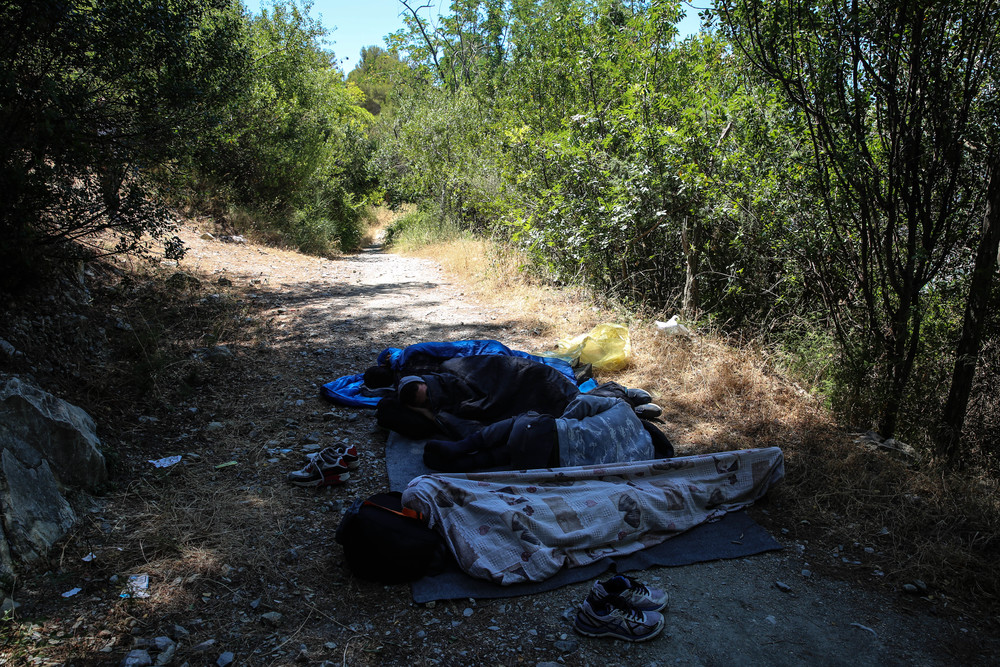 Fotografía de unos migrantes en la frontera entre Italia y Francia durmiendo en el suelo (del lado italiano) esperando a que anochezca para intentar cruzar de nuevo.