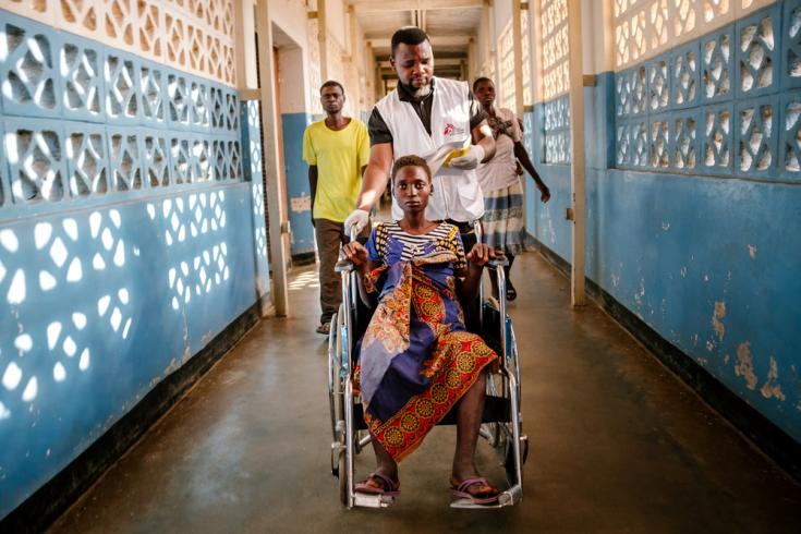 Nelson Chidanti ayudando a Lita a trasladarse en en silla de ruedas hacia otra parte del Hospital del Distrito de Nsanje