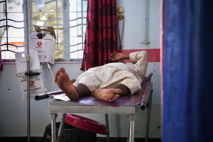 Dentro de la sala de emergencias del Hospital General al-Thawra apoyado por MSF, un paciente se encuentra en la cama después de haber sido estabilizado.