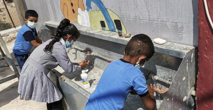 Mariam Qabas (Supervisora de Promoción de la Salud) está llevando a cabo una actividad de promoción de la salud sobre COVID-19 con niños en una escuela en Al-Ramadin, una aldea palestina ubicada al suroeste de Hebrón (Cisjordania).