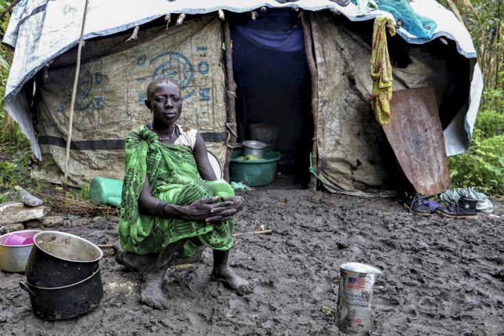 Una mujer joven sentada frente a su refugio en Lukurunyang después de que las fuertes lluvias destruyeran sus cultivos.