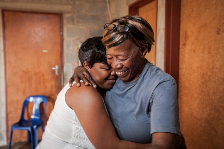 La cuidadora comunitaria Nonhlanhla Ngema en Sudáfrica abraza a un miembro de su grupo con VIH positivo.